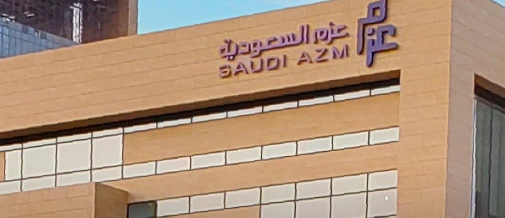 Saudi Azm company name and logo in Arabic and English on the sandstone facade of a building