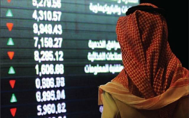 An investor looks at a screen showing sector indices at the Saudi Exchange in Riyadh