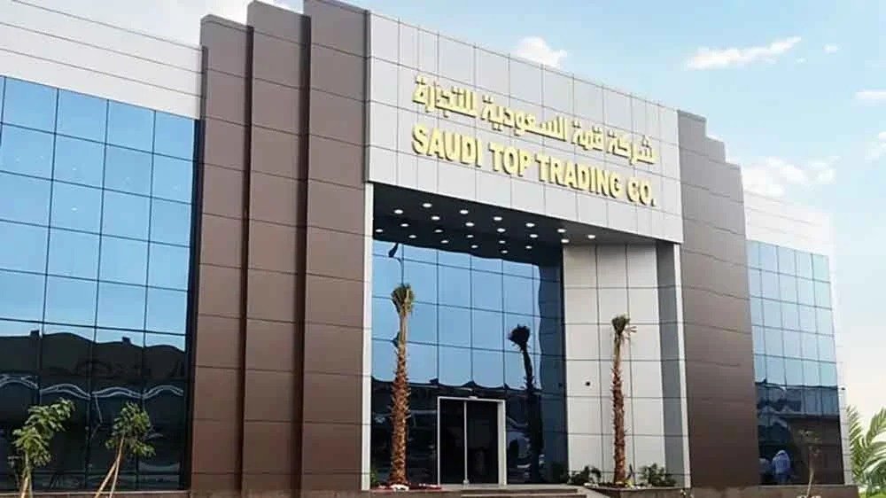 Glass and brown clad office building with the Saudi Top Trading Co. name in Arabic and English above the entrance