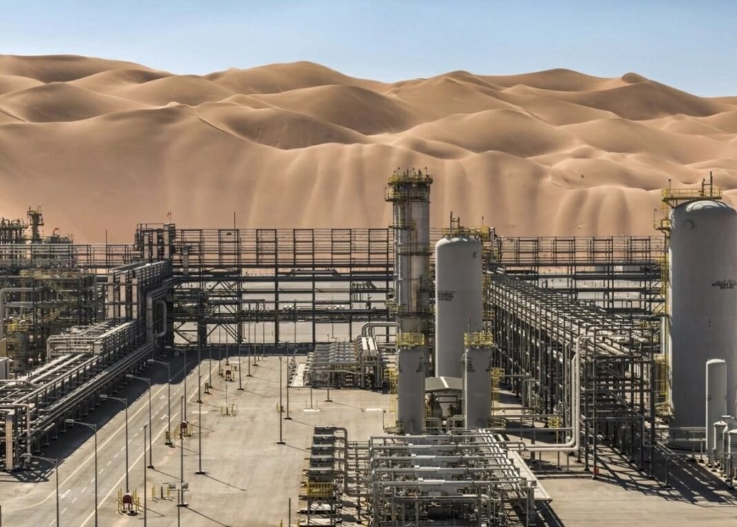 Oil processing towers, tanks and pipe racks at the Shaybah oil field with tall sand dunes behind