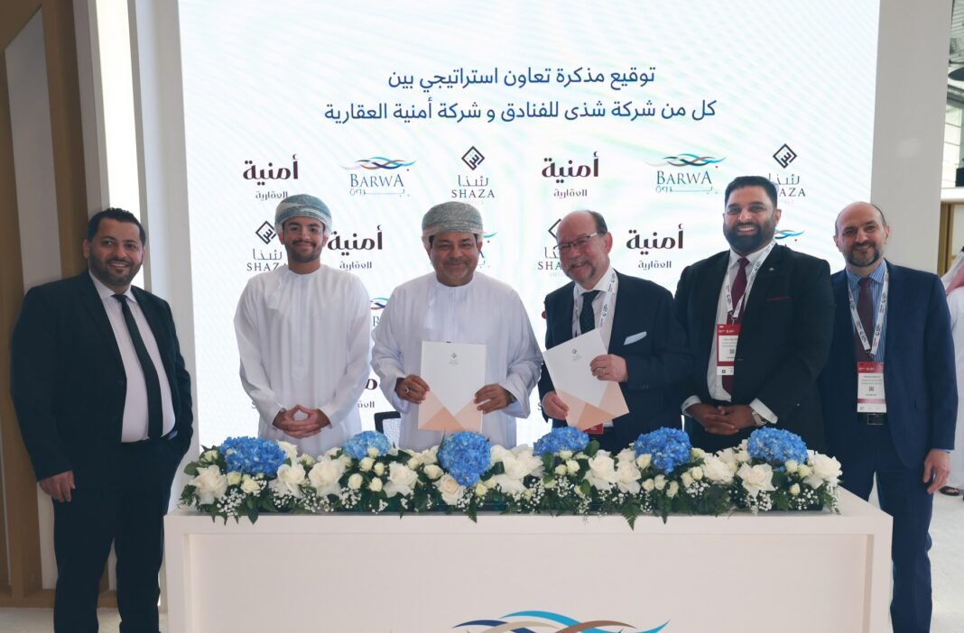 Executives of Shaza Hotels and Omnia Properties hold signed documents behind a table at the Barwa stand at Cityscape Qatar