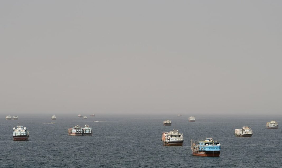Several vessels anchored on hazy water in the Strait of Hormuz seen from Musandam, Oman