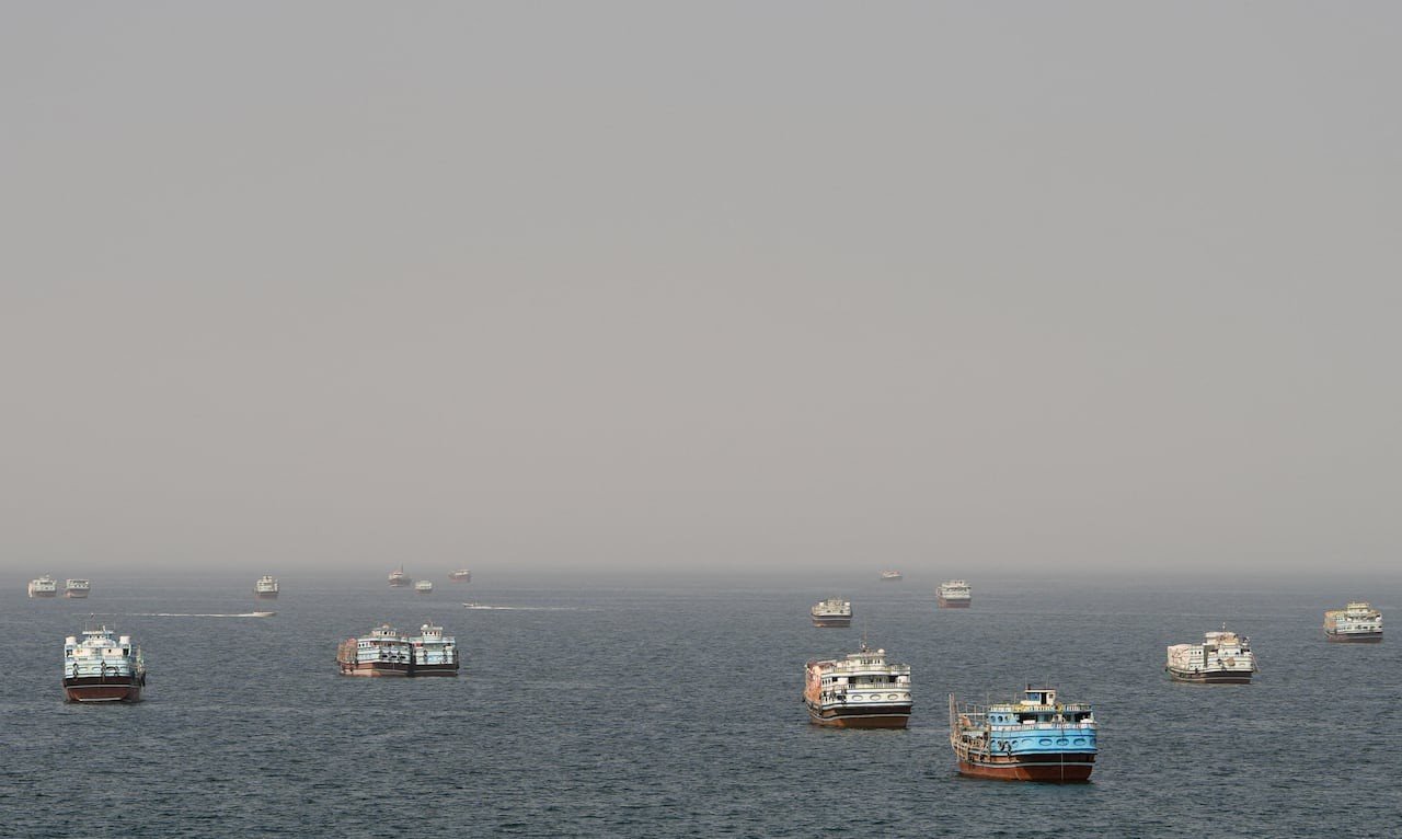 Several vessels anchored on hazy water in the Strait of Hormuz seen from Musandam, Oman