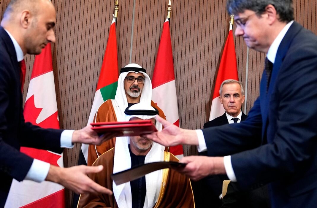 Officials exchange signed documents as Sheikh Khaled bin Mohamed bin Zayed Al Nahyan and Prime Minister Mark Carney look on in Ottawa