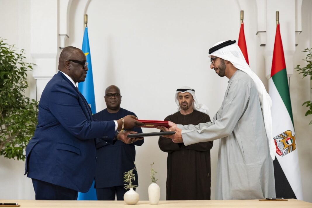 UAE Minister of Foreign Trade Thani Al Zeyoudi and DRC trade minister Julien Paluku Kahongya exchange signed agreement folders as UAE President Sheikh Mohamed bin Zayed and DRC President Felix Tshisekedi look on