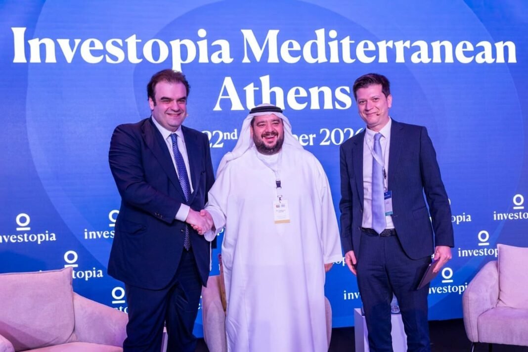 Three men shaking hands on stage in front of an Investopia Mediterranean Athens backdrop