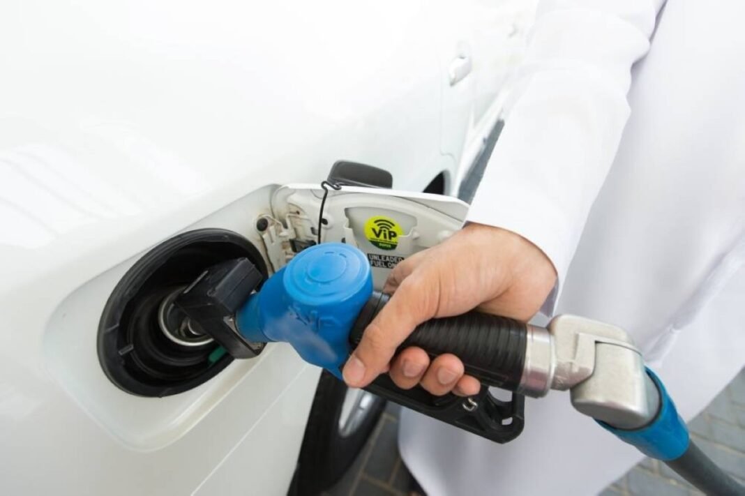 A motorist holds a fuel nozzle while refueling a white car in the UAE