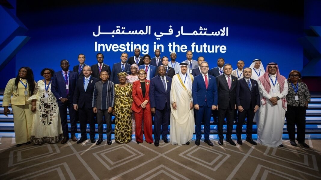 Officials and delegates stand for a group photo on stage at the World Investment Forum 2026 in Doha, under a banner reading Investing in the future in Arabic and English