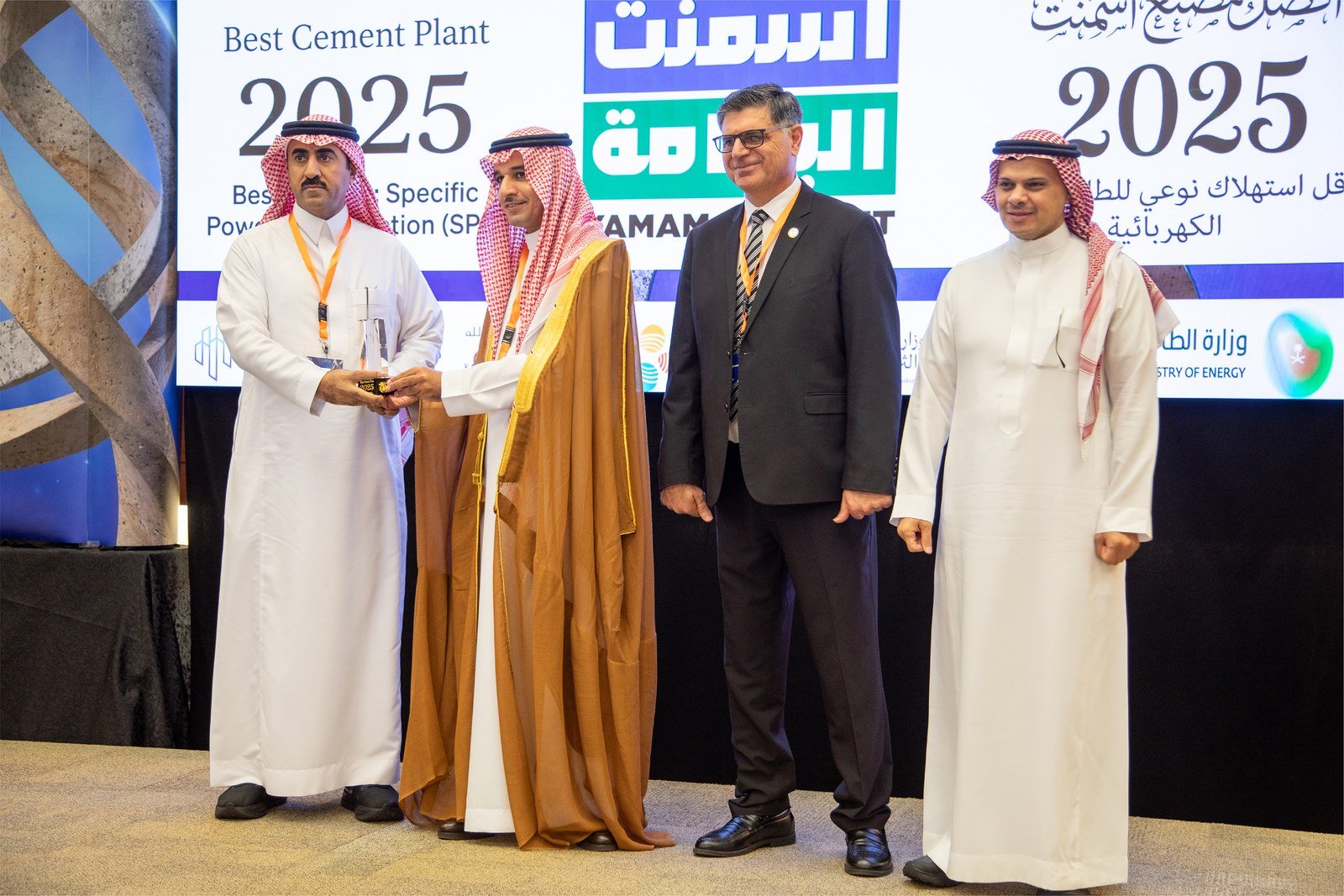 Four men on a stage holding an award in front of a screen reading Best Cement Plant 2025 and Yamama Cement